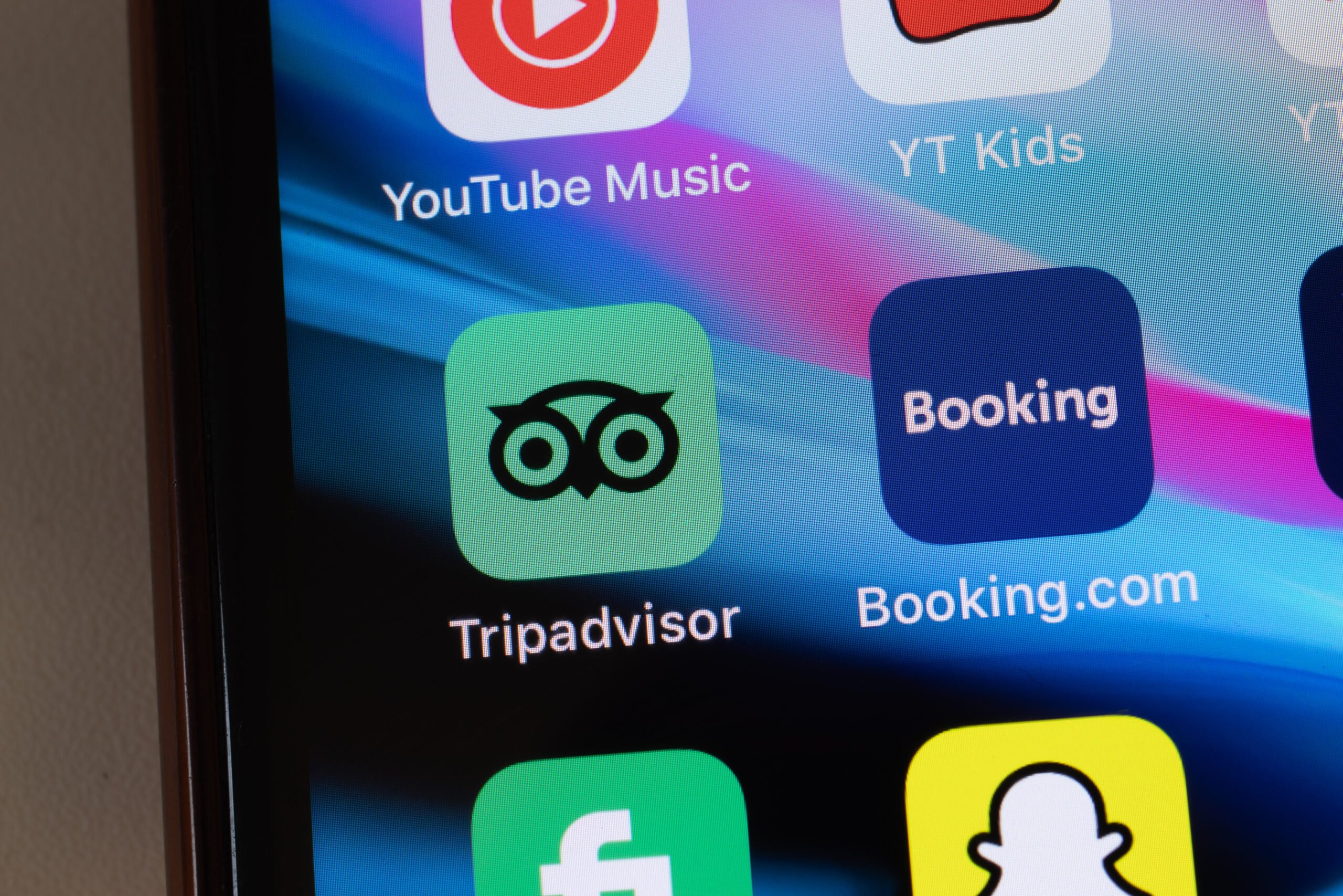 Ekran telefonu z ikonami aplikacji, w tym TripAdvisor, Booking.com, YouTube Music, YT Kids i Snapchat.