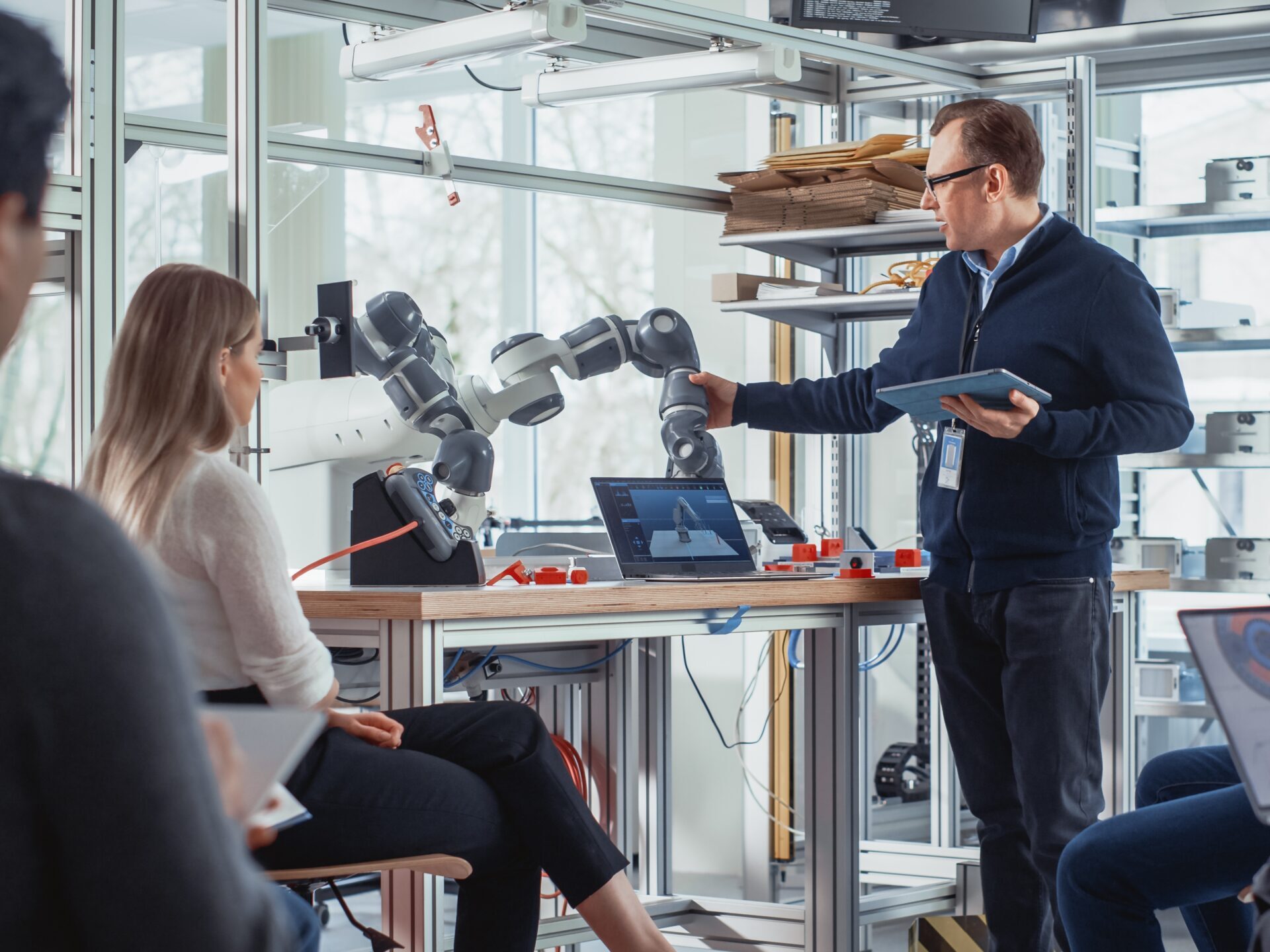 AI w pracy. Ludzie w laboratorium dyskutujący na temat robota przemysłowego.