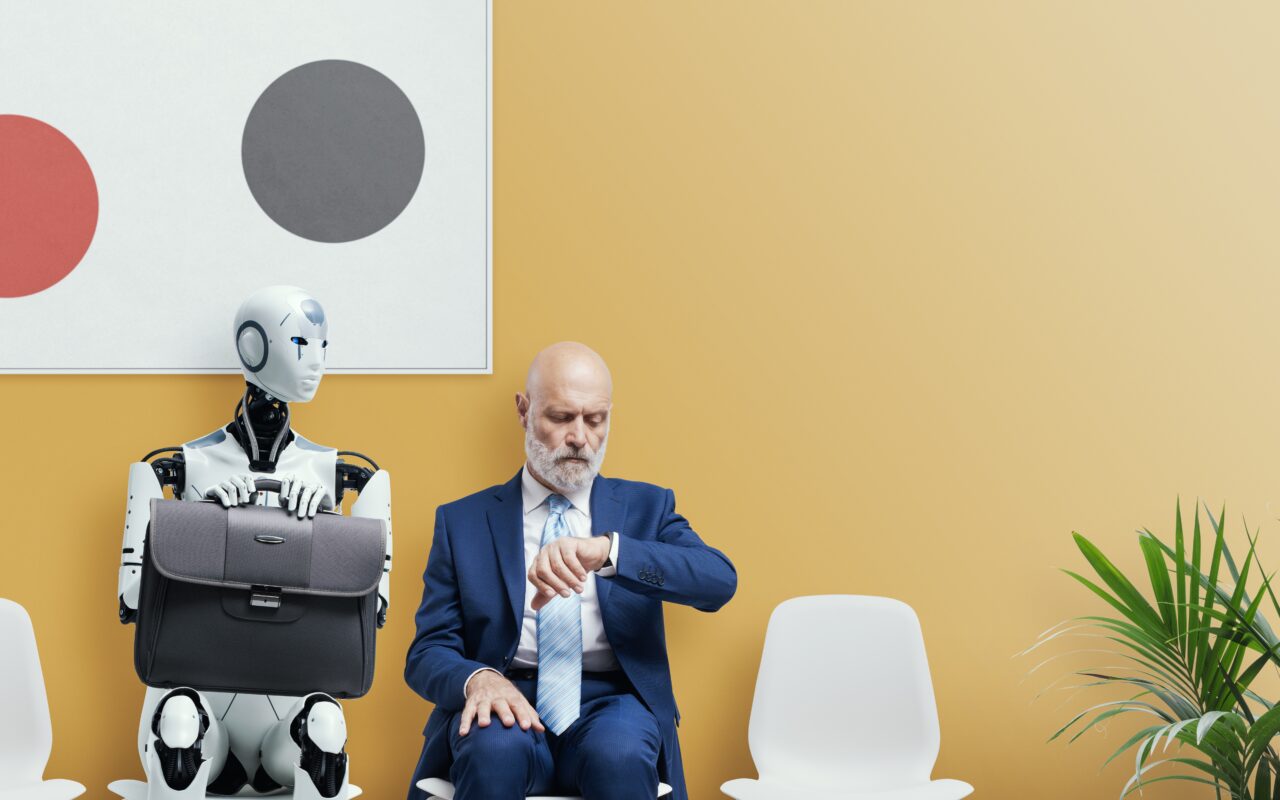 Robot i mężczyzna w garniturze siedzący obok siebie, mężczyzna patrzy na zegarek, robot trzyma teczkę.