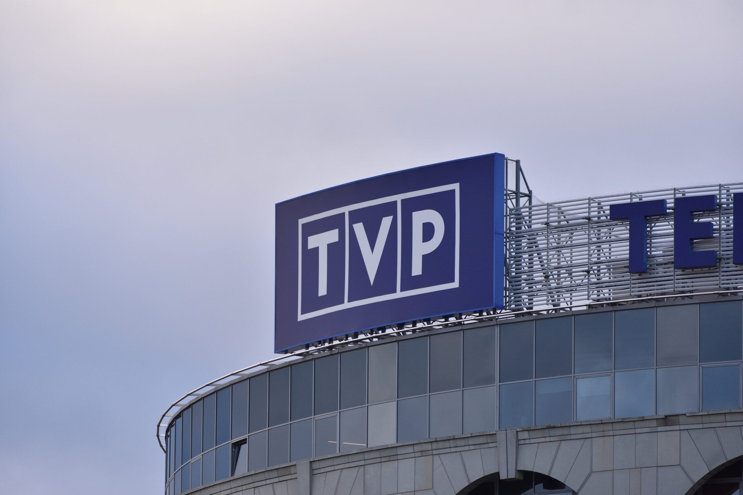 Szyld z logo TVP na budynku.