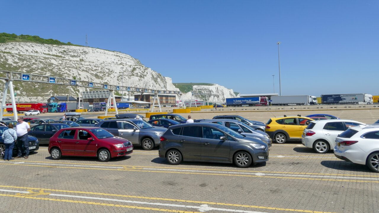 Ludzie i samochody zaparkowane na parkingu przed wjazdem na prom przy białych klifach w Dover.