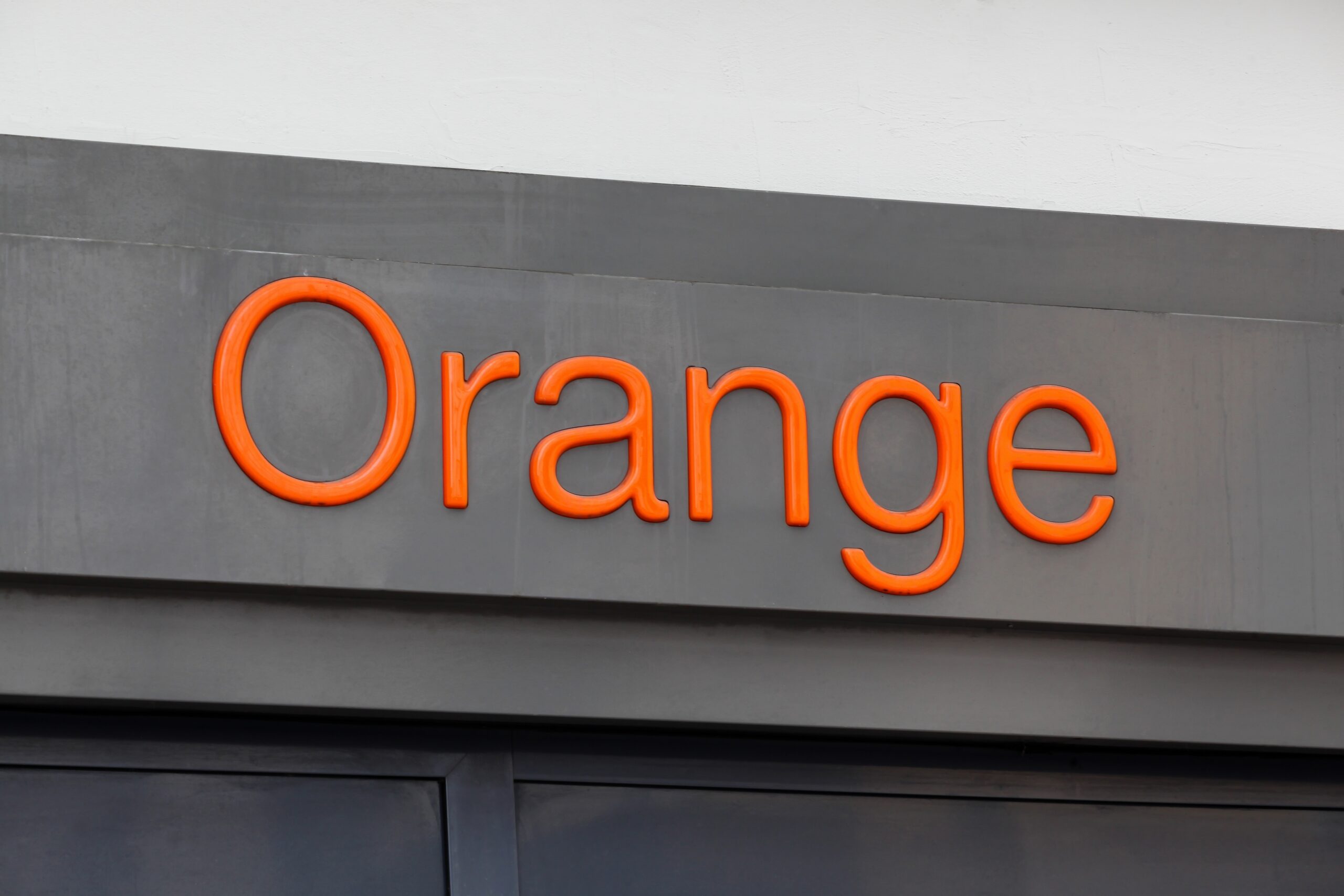 Pomarańczowy napis "Orange" na ciemnoszarym tle.