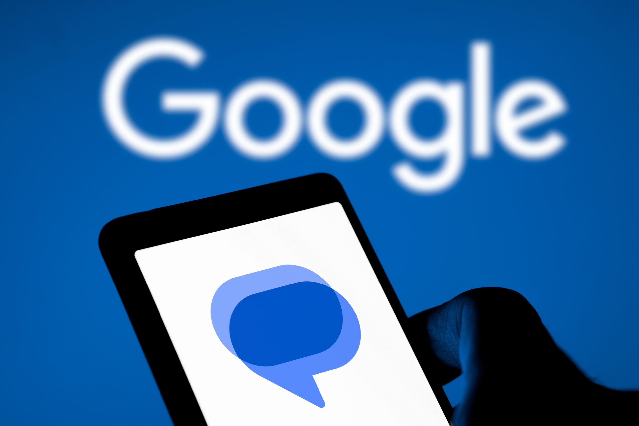 Logo Google na niebieskim tle oraz ikona aplikacji z dymkiem do rozmów na ekranie smartfona.