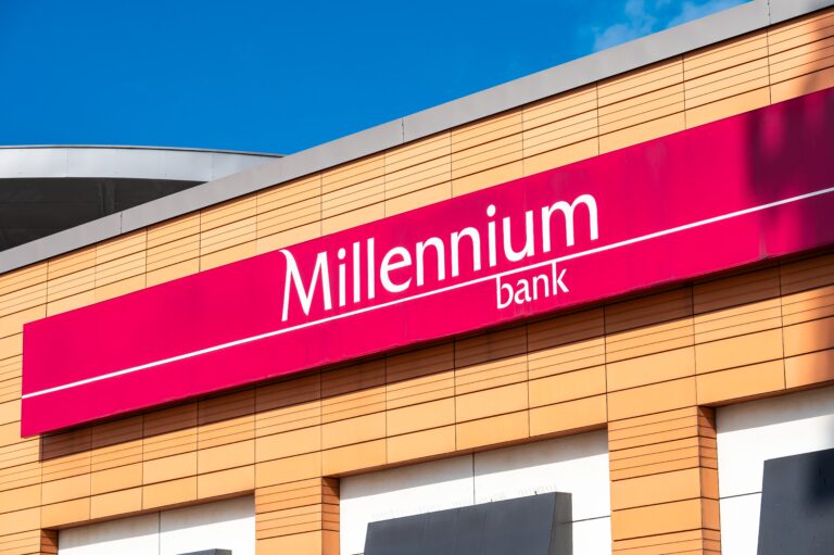 Sztandar banku Millennium na tle nowoczesnego budynku.