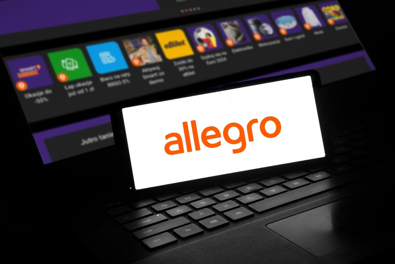 Allegro Delivery to nowy program szybkich dostaw. Smartfon z logiem allegro, w tle laptop z otwartą stroną allegro