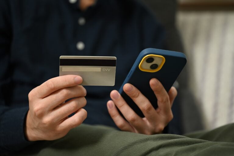 Osoba trzymająca kartę kredytową i smartfon.