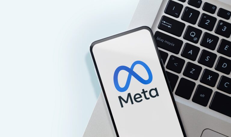 Smartfon z logo Meta leżący na klawiaturze laptopa.
