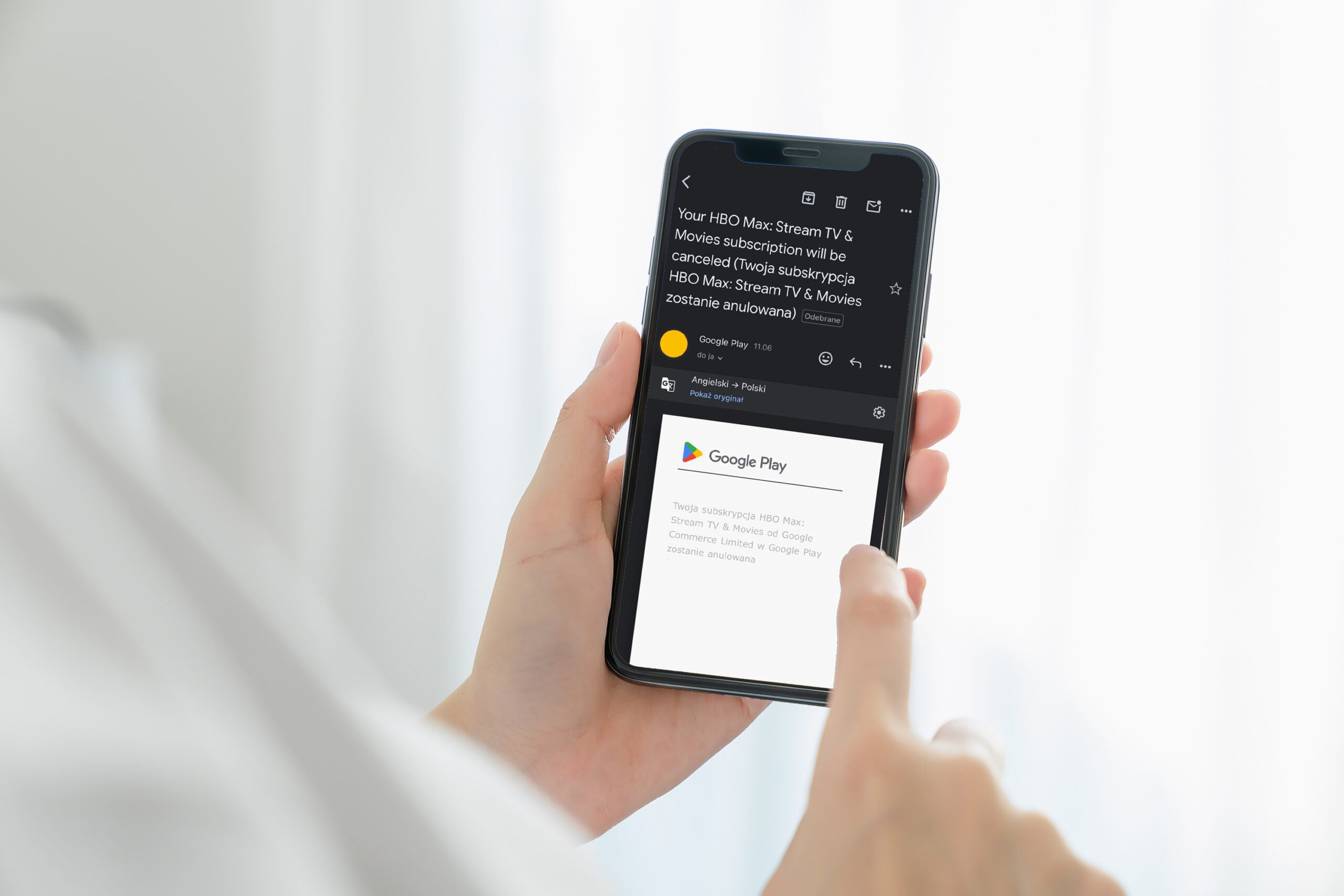 Osoba trzymająca telefon z widoczną wiadomością e-mail zawiadamiającą o anulowaniu subskrypcji HBO Max, wysłaną przez Google Play.