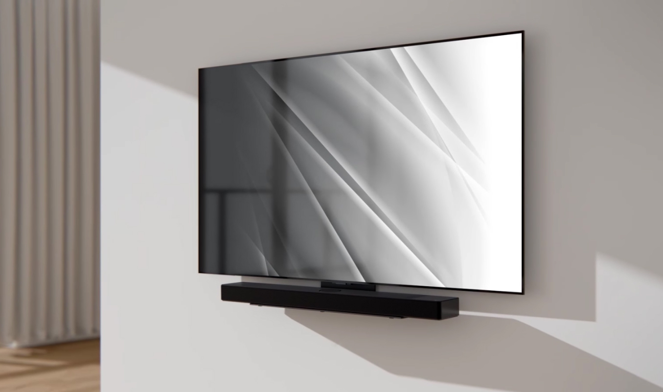 Telewizor zamontowany na ścianie z czarnym soundbarem poniżej.