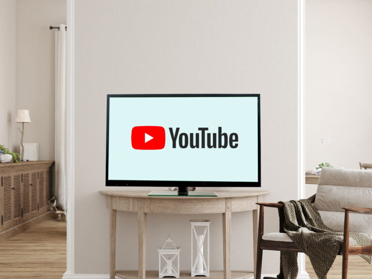 Telewizor wyświetlający logo YouTube, ustawiony na drewnianym stole w jasnym salonie.