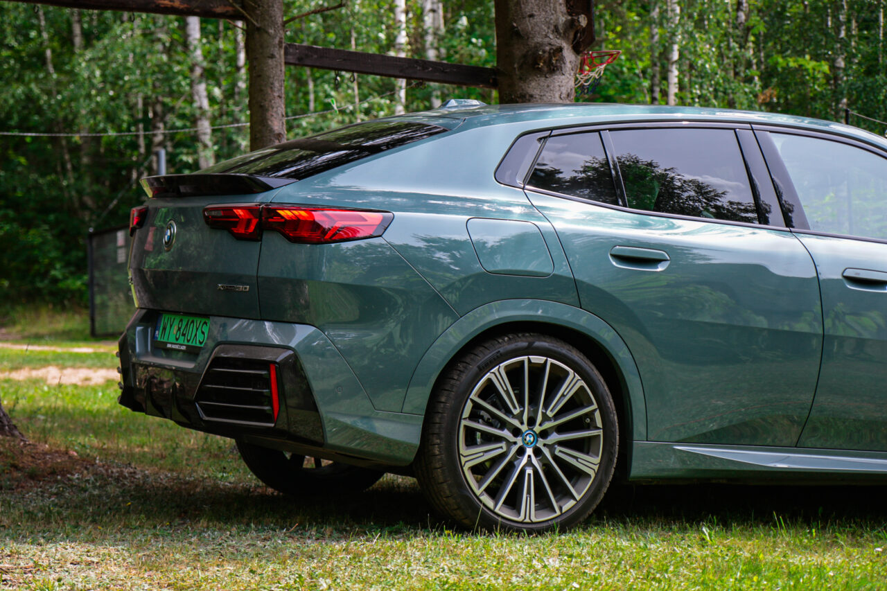 Tył zielonego samochodu BMW iX2 w lesie podczas testu