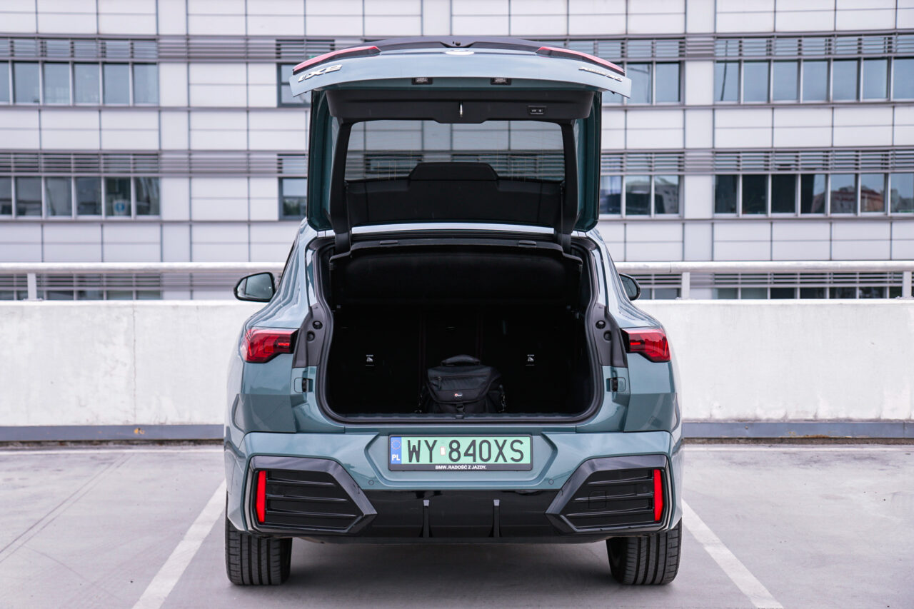 Widok otwartego bagażnika samochodu BMW iX2 na parkingu, test BMW iX2.