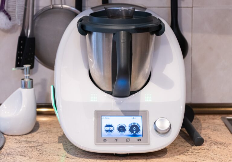 Robot kuchenny Thermomix TM6 na blacie, z wyświetlaczem dotykowym i metalowym dzbankiem.