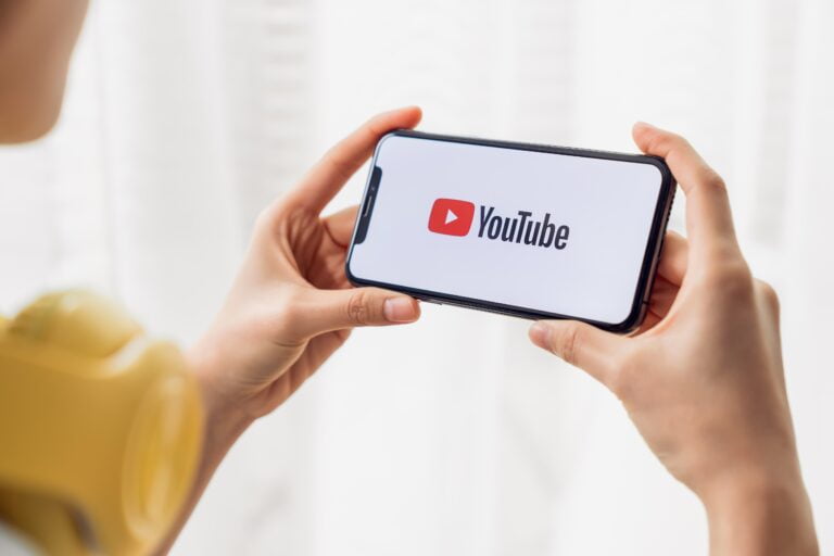 Osoba trzymająca telefon z logo YouTube na ekranie.