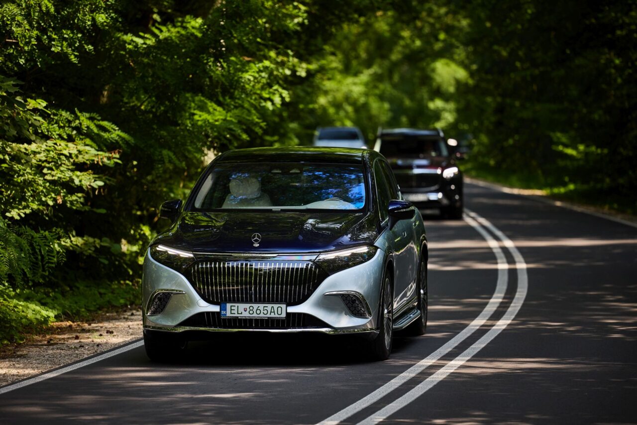 Samochód Mercedes jadący drogą w otoczeniu zielonego lasu.