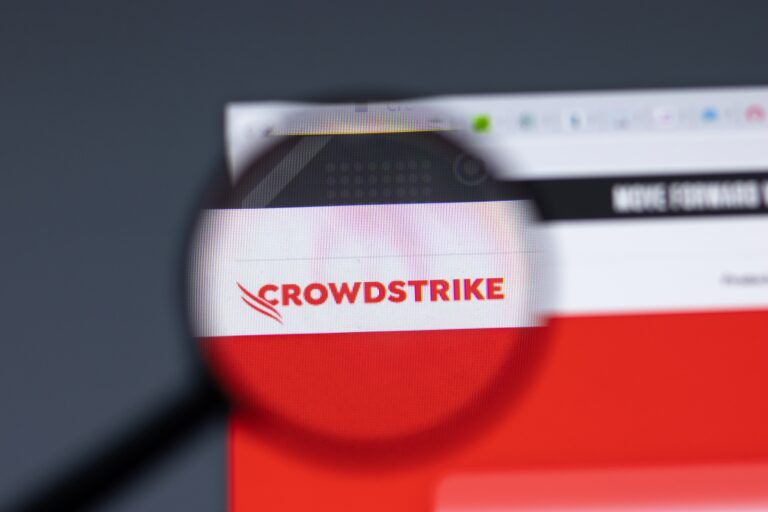 Logo CrowdStrike widziane przez lupę na ekranie komputera.