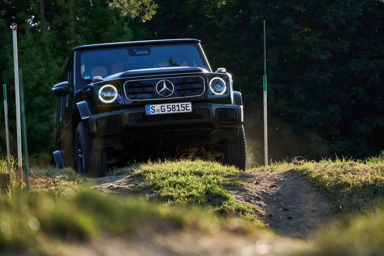 Czarny Mercedes-Benz G-Klasa porusza się po nierównym terenie.