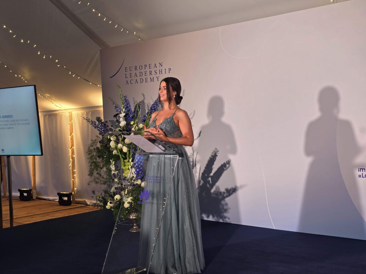 Huawei Summer School for Female Leadership Farewell Gala. Kobieta w sukni wieczorowej przemawia na podium podczas gali w European Leadership Academy.