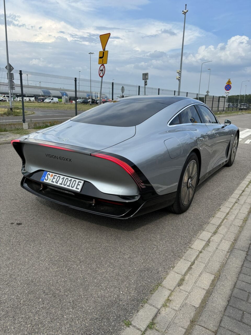 Srebrny samochód Mercedes-Benz Vision EQXX zaparkowany na poboczu, widok z tyłu.