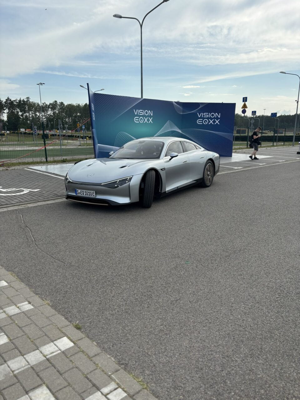 Srebrny samochód Mercedes-Benz Vision EQXX na tle billboardu.