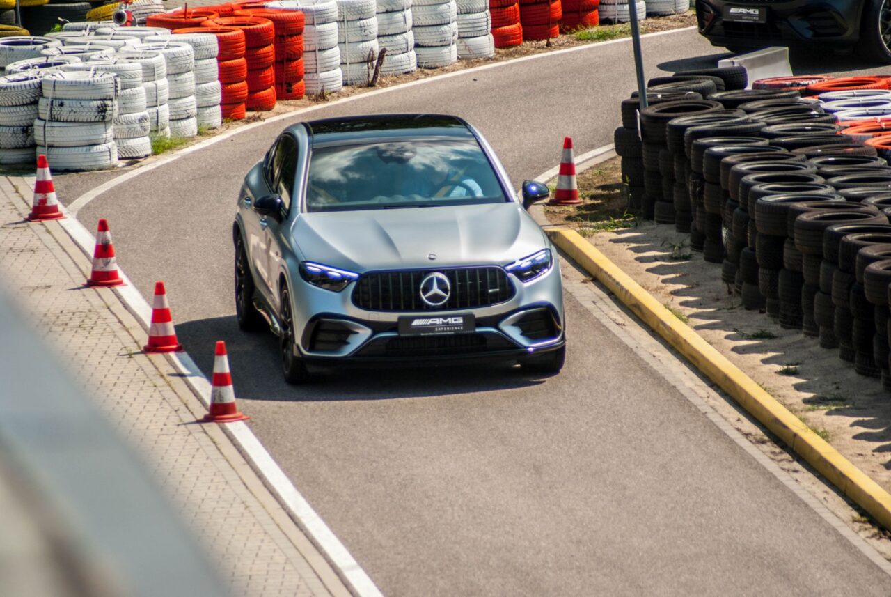 Samochód Mercedes-AMG pokonujący zakręt na torze wyścigowym, otoczony oponami i pachołkami.