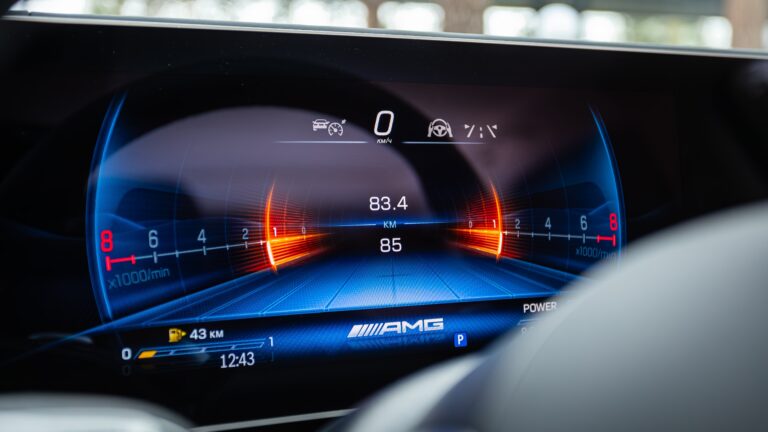 Cyfrowy wyświetlacz deski rozdzielczej samochodu AMG, prezentujący prędkość, obroty silnika i poziom paliwa.