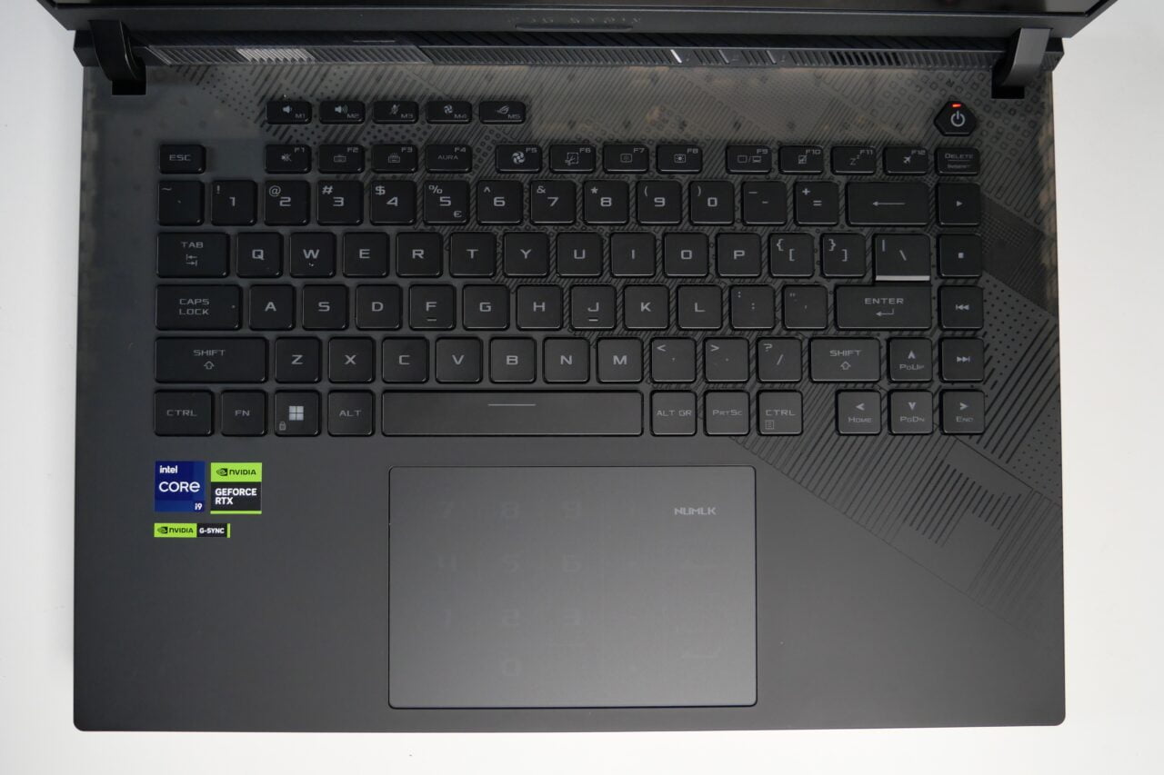 Czarno-szara klawiatura laptopa z naklejkami Intel Core i9, NVIDIA GeForce RTX i NVIDIA G-SYNC, wbudowanym touchpadem z funkcją numeryczną.