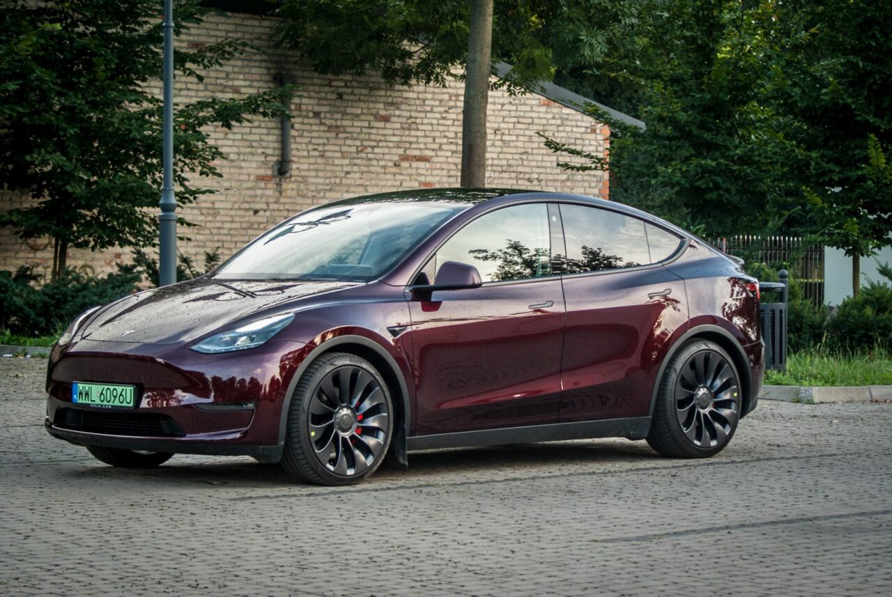 Czerwony Tesla Model Y Performance zaparkowany na brukowanej ulicy.