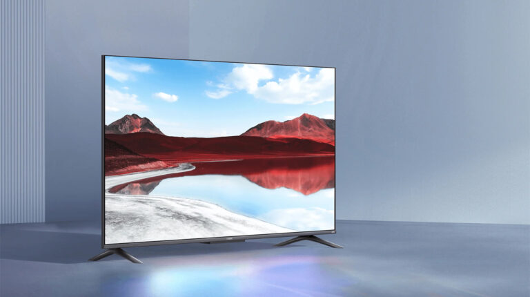 Nowoczesny telewizor z cienką ramką, wyświetlający krajobraz z czerwonymi górami i błękitnym niebem.