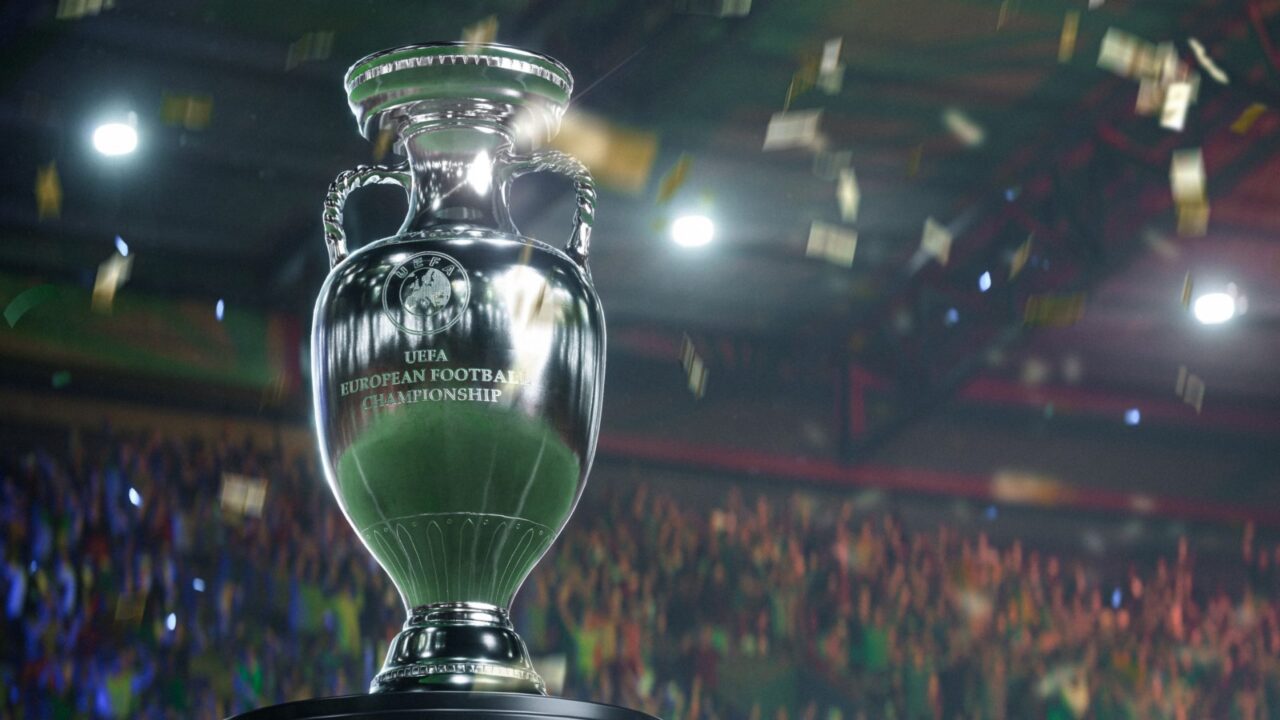 Trofeum Mistrzostw UEFA EURO 2024 na tle rozmytego stadionu. To zrzut ekranu z EA Sports FC 2024