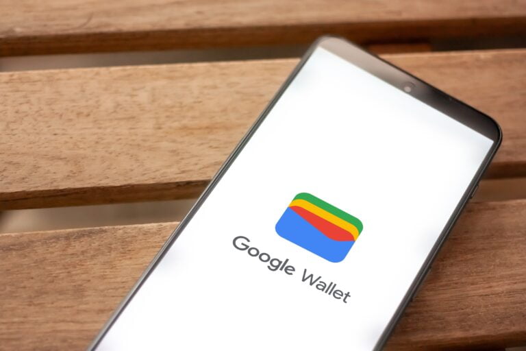 Smartfon z aplikacją Google Wallet na ekranie, leżący na drewnianym stole.