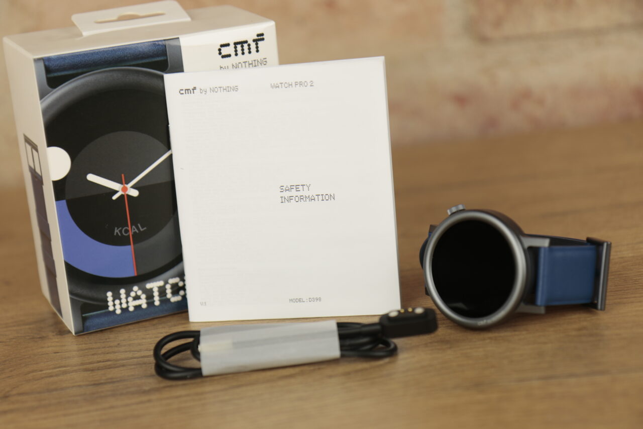 Recenzja CMF Watch Pro 2 - pudełko, instrukcja, smartwatch i kabel do ładowania na stole.