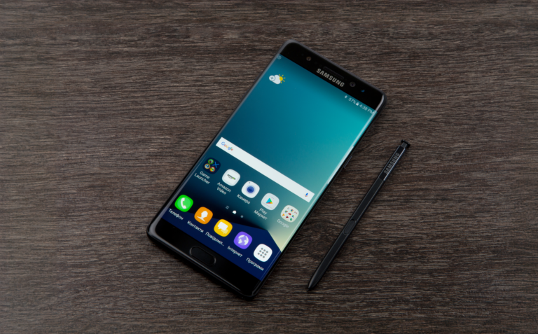 Smartfon Samsung Galaxy Note 7 leżący na drewnianym blacie.