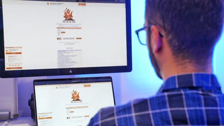 Osoba przeglądająca stronę internetową The Pirate Bay na dwóch monitorach komputerowych.