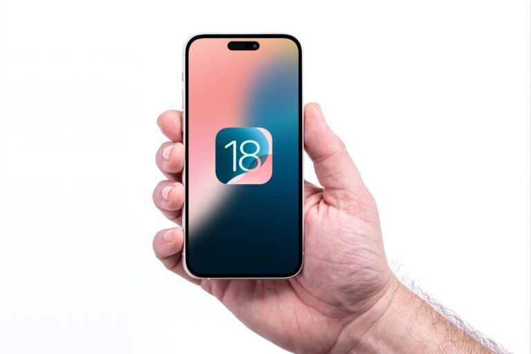 Dłoń trzymająca smartfon z ikoną przedstawiającą numer 18 na ekranie.