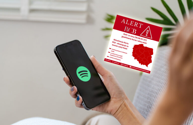 Osoba trzymająca smartfon z logo aplikacji Spotify na ekranie, w tle wydrukowany alert RCB dotyczący przewidywanych burz i silnego wiatru w całej Polsce.