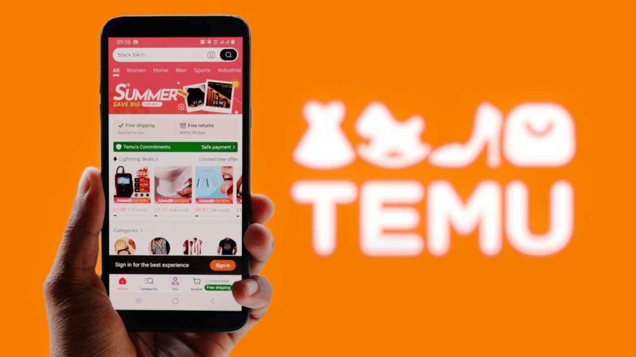 Osoba trzymająca smartfona z aplikacją zakupową Temu na ekranie, w tle logo Temu na pomarańczowym tle.
