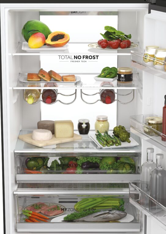 Wnętrze lodówki z różnymi produktami spożywczymi, w tym owocami, warzywami, serami, mięsem, rybą, kawą, dżemem, jogurtem i winem.