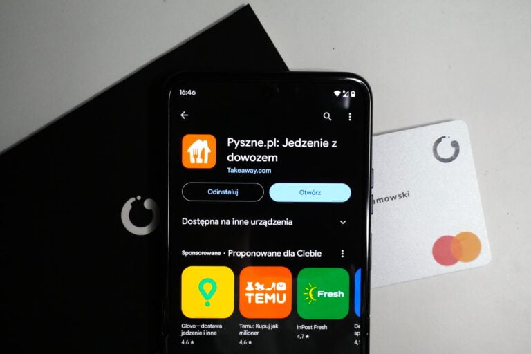 Smartfon wyświetlający aplikację Pyszne.pl oraz kartę płatniczą leżącą na stole.
