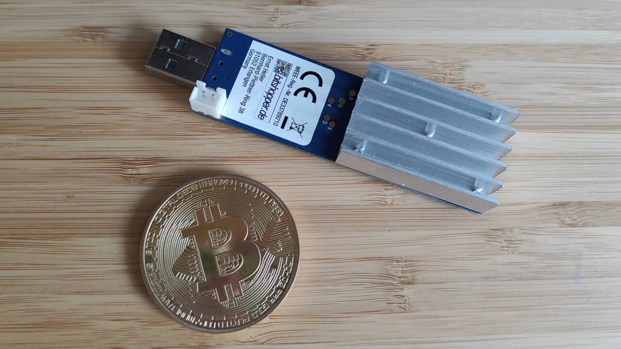 koparka USB dla kryptowalut. Moneta Bitcoin i koparka USB na drewnianym tle