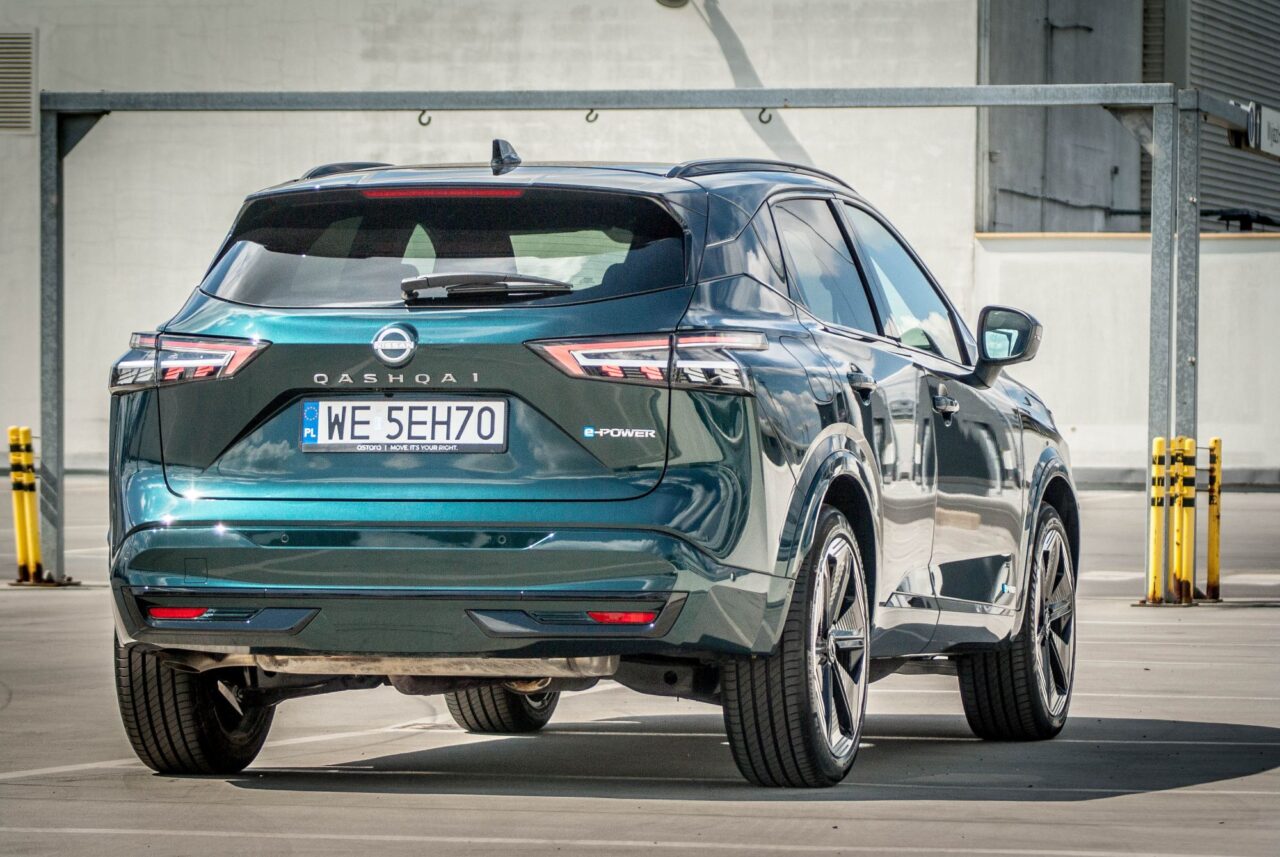 Niebieski Nissan Qashqai e-Power widziany od tyłu na parkingu, z polską tablicą rejestracyjną WE 5EH70.