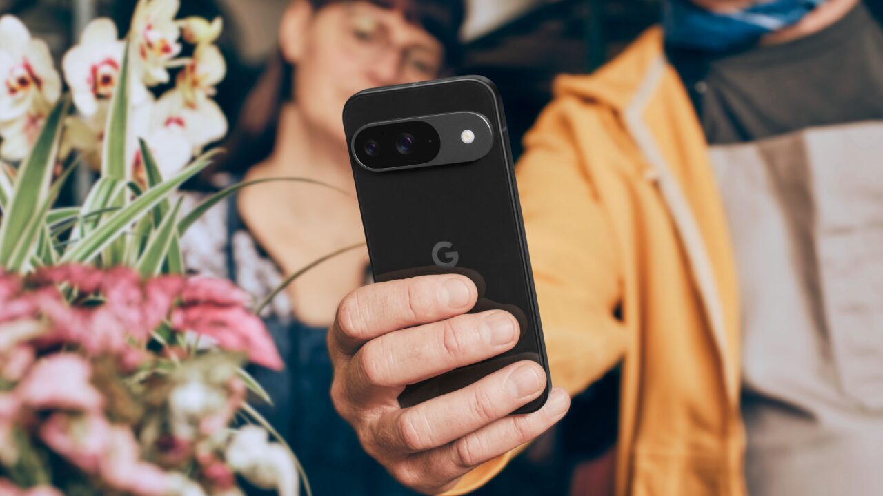 Osoba trzymająca telefon Google Pixel z kwiatami w tle.