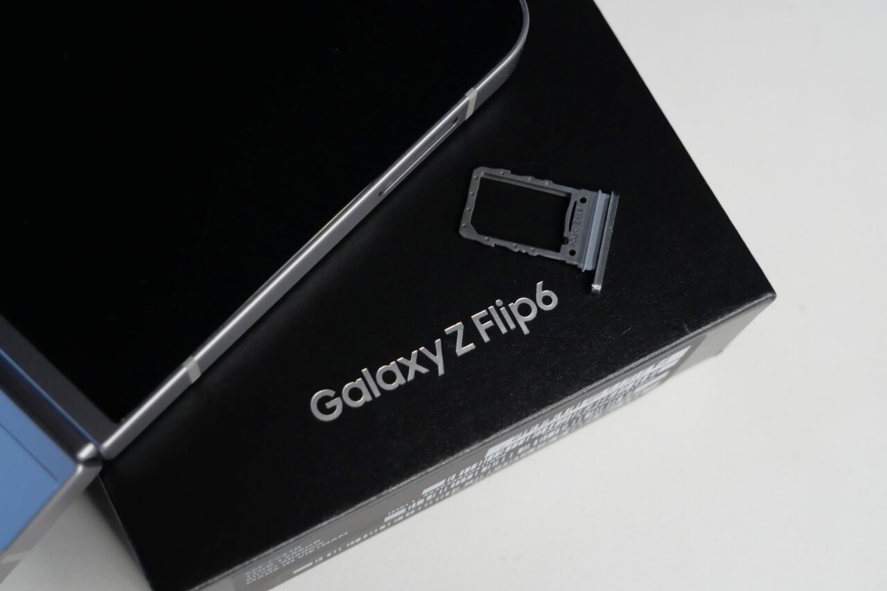 Telefon Samsung Galaxy Z Flip6 na pudełku z wyciągniętą tacką na kartę SIM.