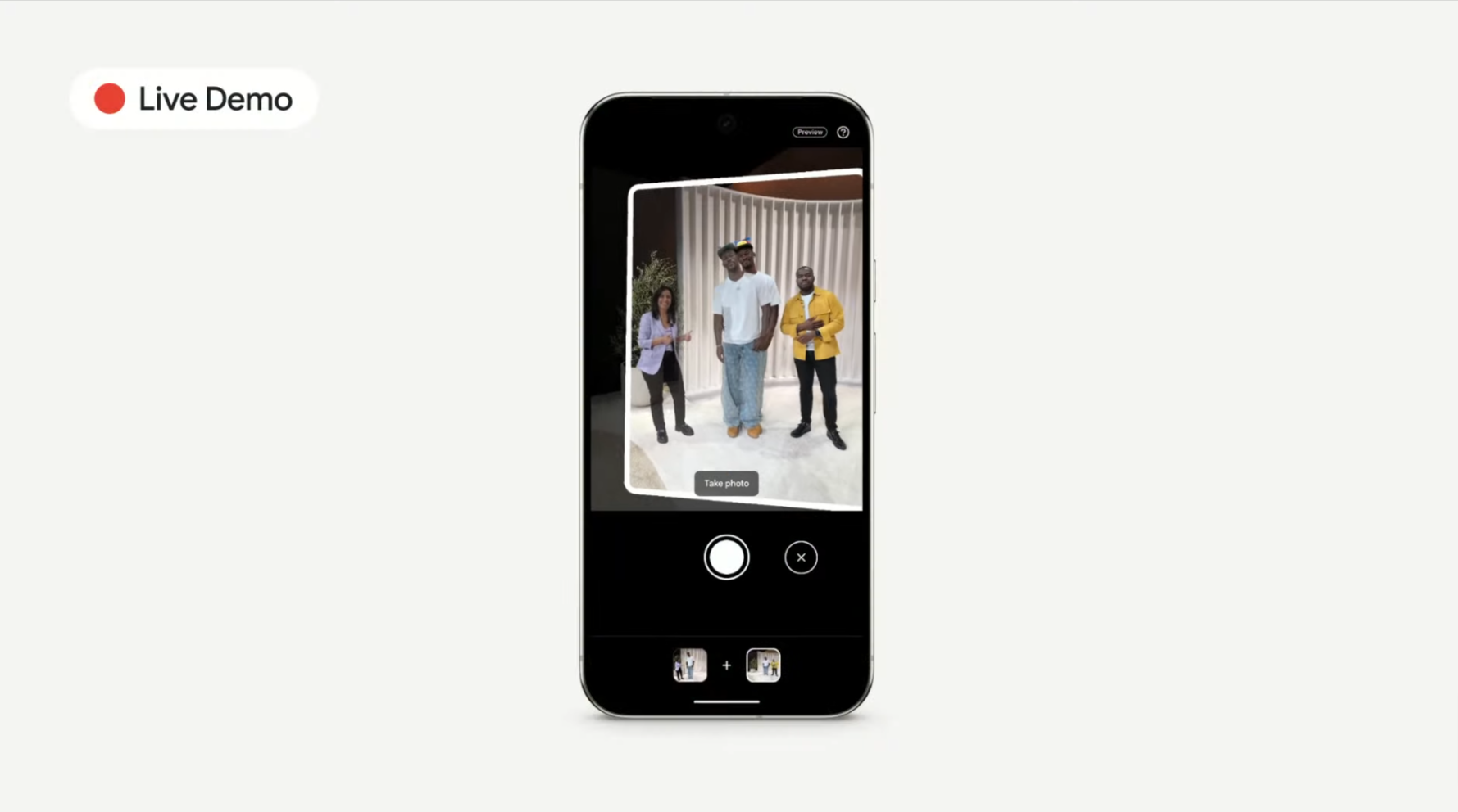 Google AI funcja add me w aparacie. Telefon komórkowy wyświetlający na ekranie aplikację aparatu z trzema osobami w kadrze i przyciskiem "Take photo".