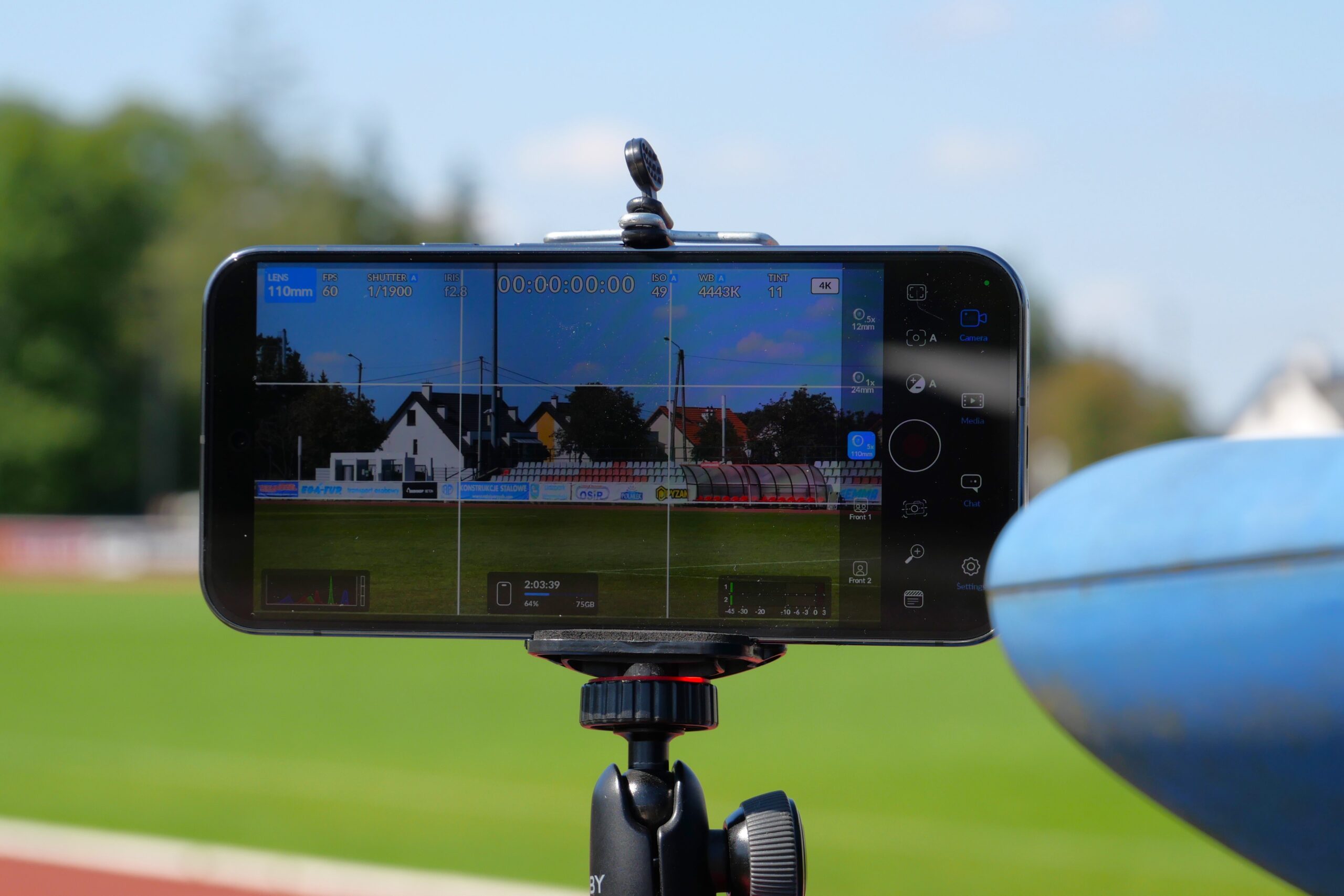 Smartfon na statywie nagrywający stadion piłkarski.