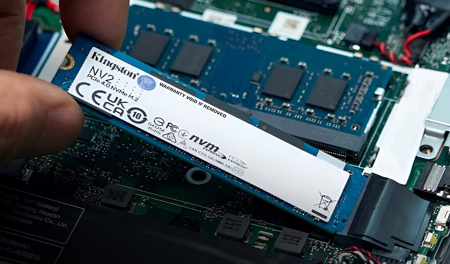 Osoba trzymająca dysk SSD Kingston NV2 PCIe 4.0 NVMe M.2 w komputerze.