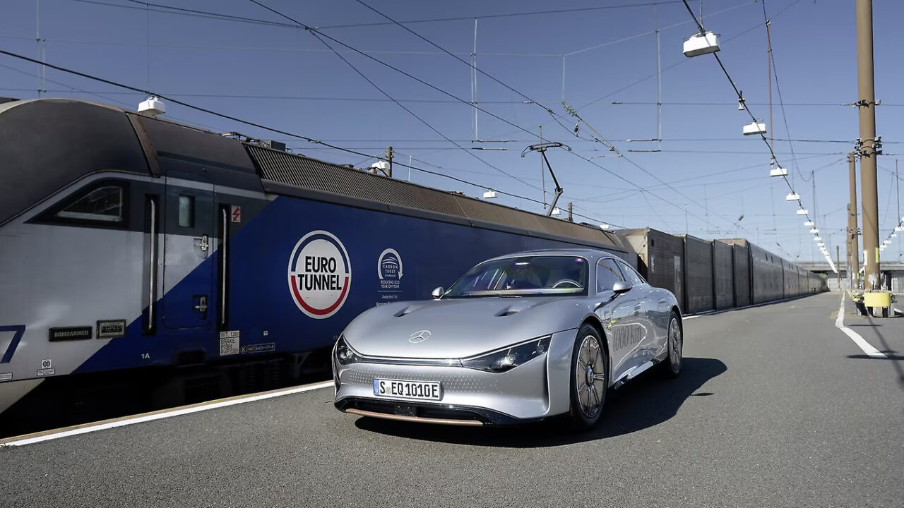 Srebrny samochód Mercedes przed pociągiem Eurotunel na stacji kolejowej.