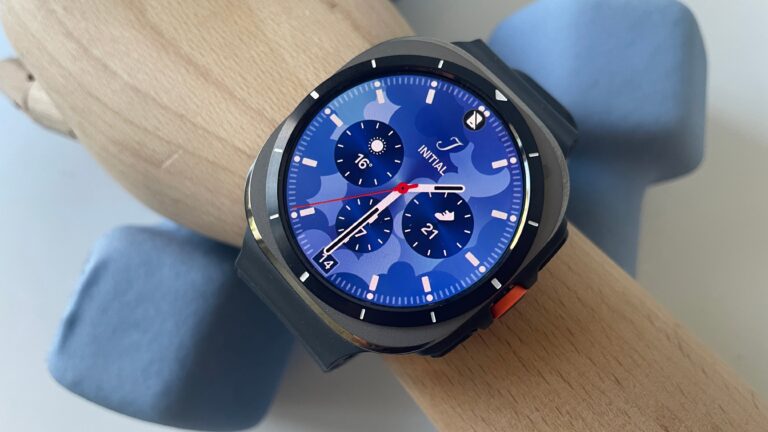 recenzja samsung galaxy watch ultra. Smartwatch z okrągłą niebieską tarczą i czarnym paskiem, leżący na drewnianej powierzchni.