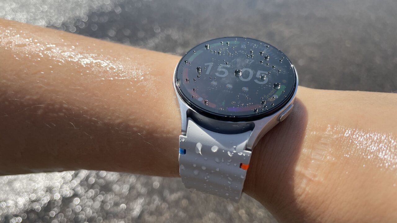 Zegarek Samsung Galaxy Watch 7 na ręce z kroplami wody na ekranie.