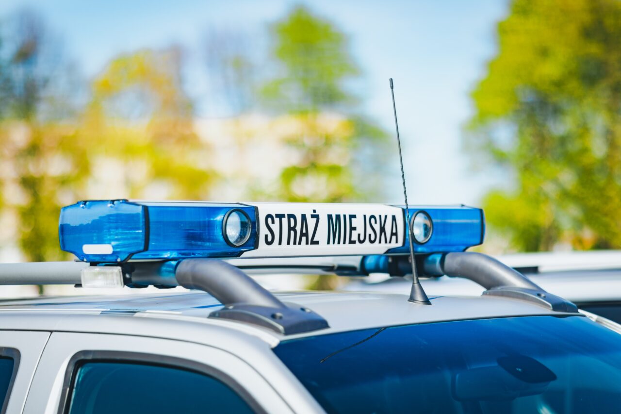 Radiowóz straży miejskiej z niebieskim sygnalizatorem świetlnym.